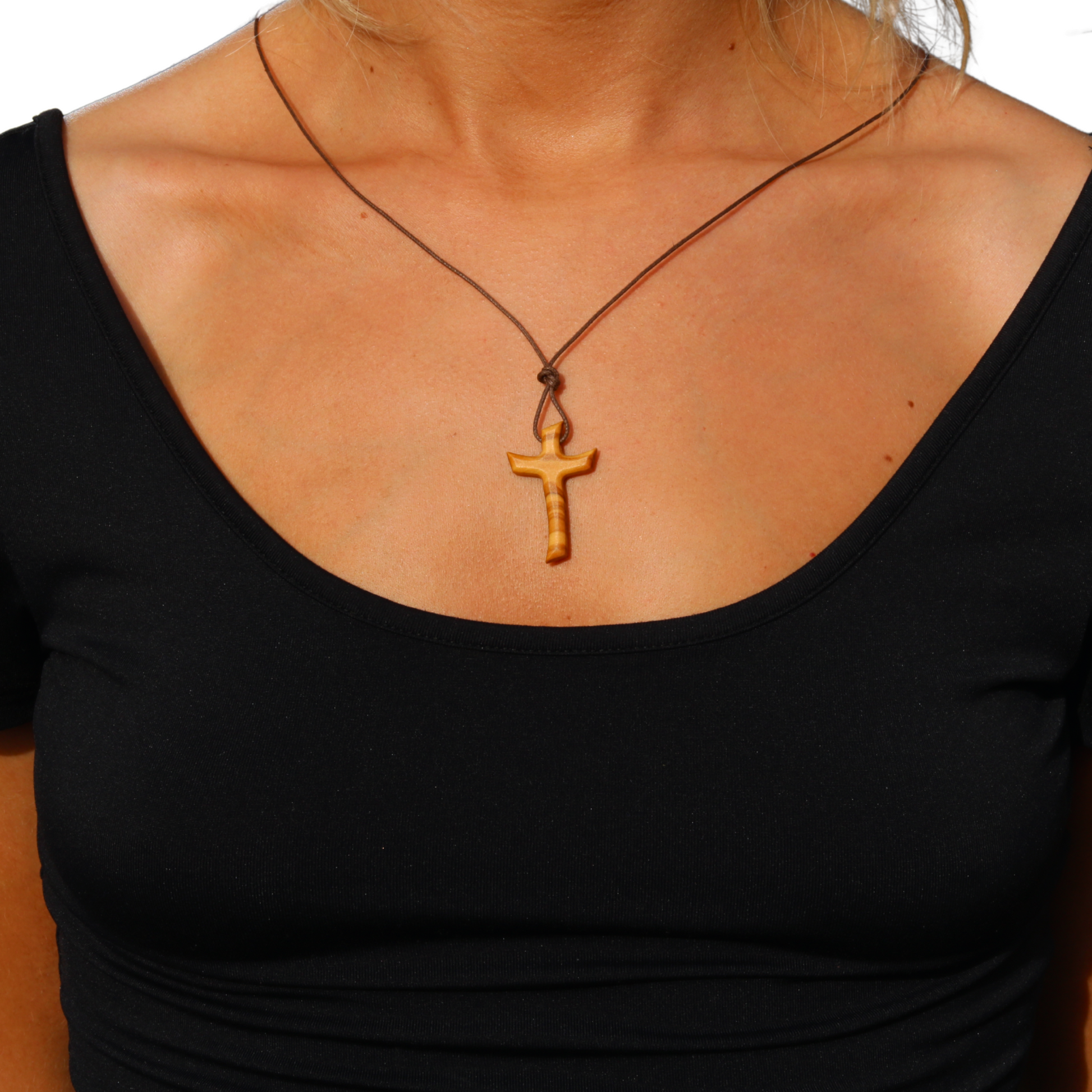 Person wearing a black top with a necklace featuring a wooden cross pendant.
