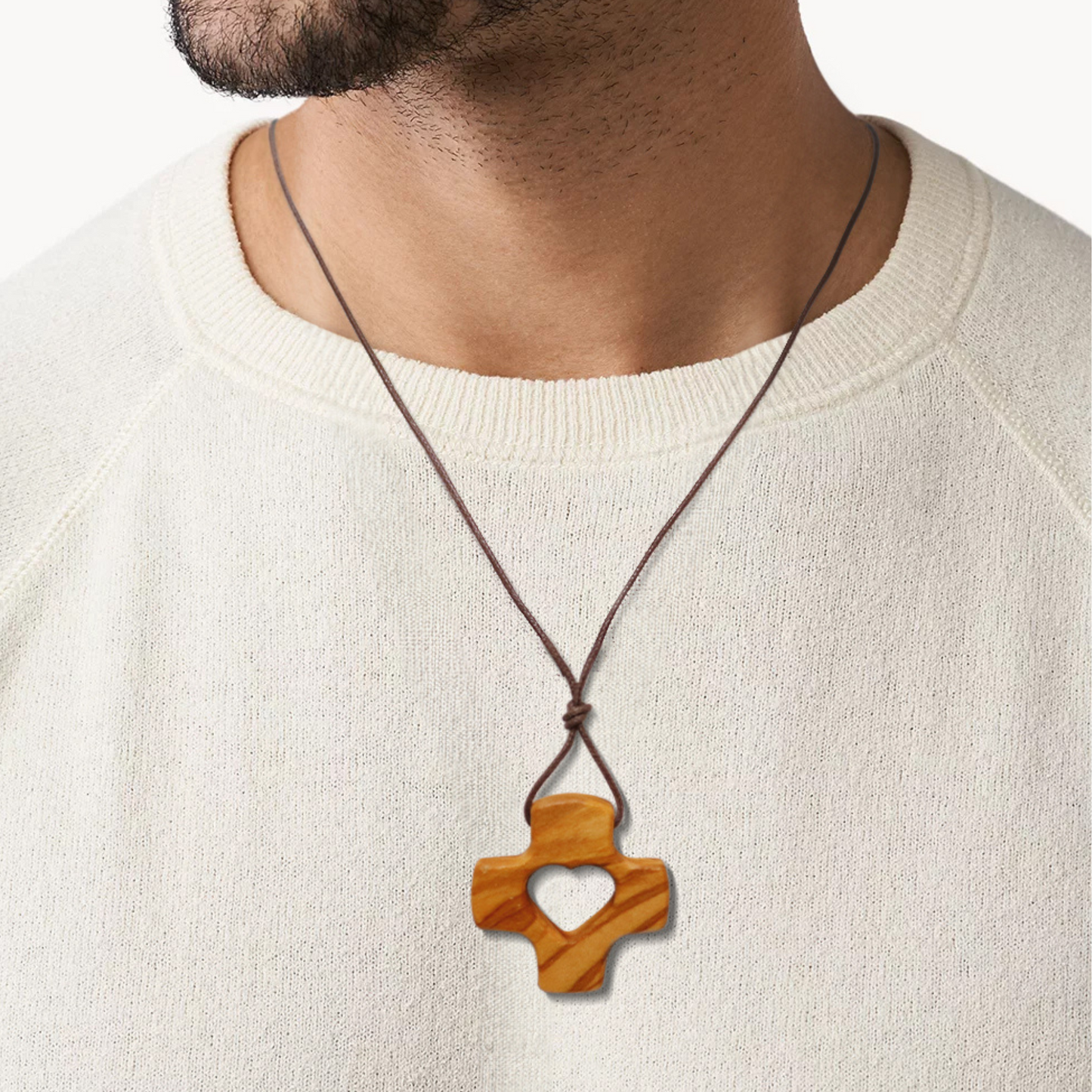 Wooden cross pendant necklace on a person wearing a white sweater