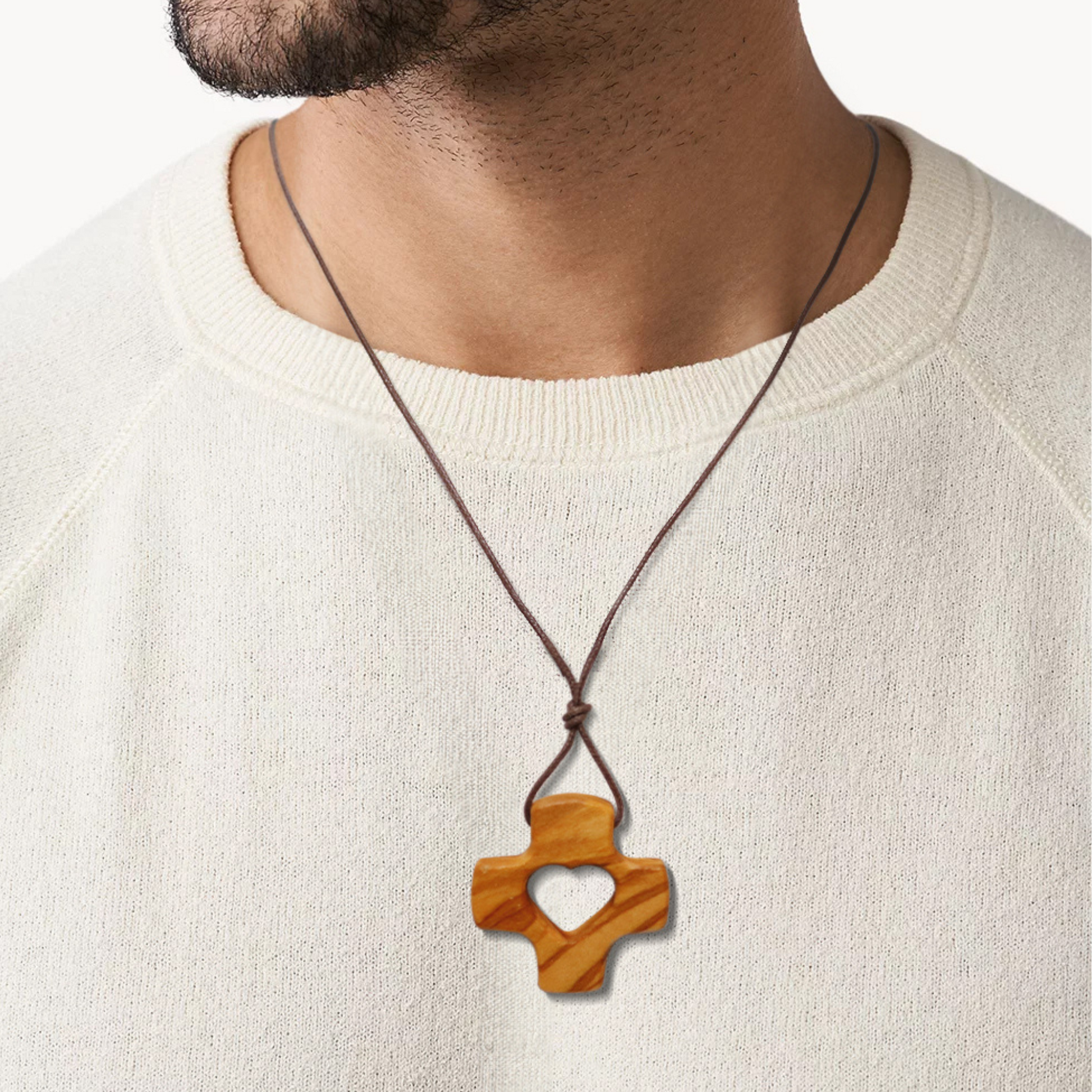 Wooden cross pendant necklace on a person wearing a white sweater