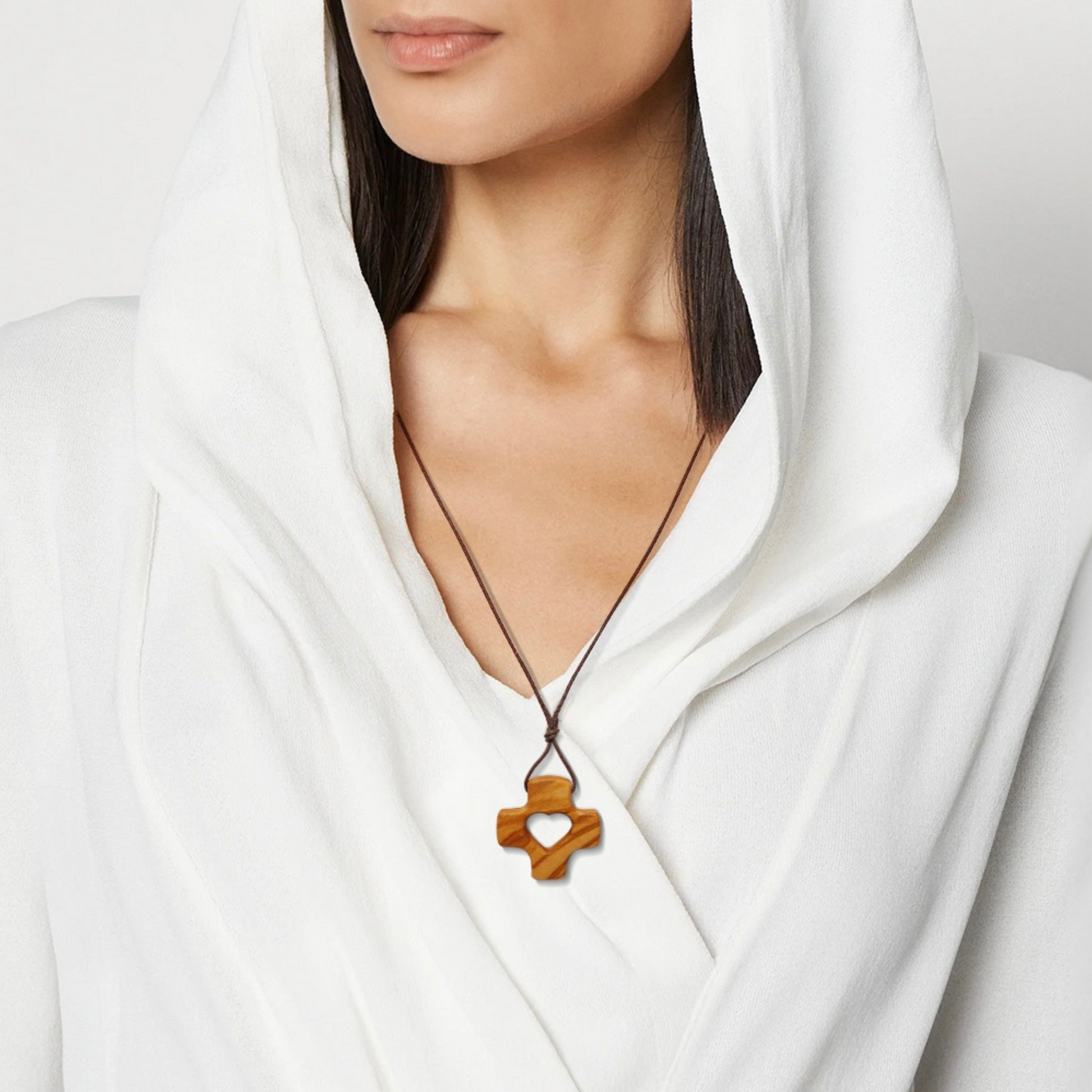Woman wearing a white outfit with a necklace featuring a wooden pendant.