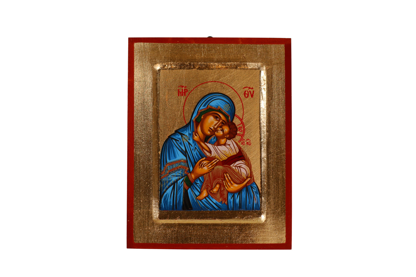 A hand-painted icon of the Virgin Mary in a blue robe cradling the infant Jesus against a golden background, within a red frame. Mary has a contemplative expression and a halo inscribed with "MP OY," while Jesus looks outward with a hand raised in blessing and a halo with a cross.