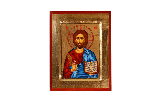 An Eastern Orthodox icon of Jesus Christ centered within a red frame, featuring Christ with a solemn expression, haloed head, blessing with His right hand, and holding an open book in His left. The halo bears the Greek letters "IC XC," and He is robed in red and blue with golden highlights, set against a golden background.