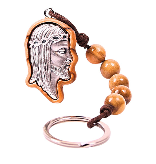 Olive wood pendant keychain featuring a silver-toned metal profile of Jesus' face encased in a carved olive wood frame, with five olive wood beads extending from the pendant and attached to a silver-toned metal ring.