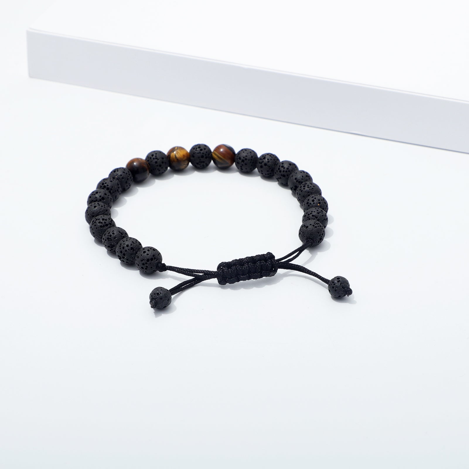 Lava Bead Bracelet with Tiger Eye Accents Displayed Near Elevated White Platform