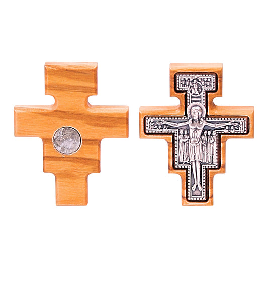 An olive wood San Damiano cross magnet, shown from both front and back views side by side. The front features a silver-toned metal overlay with embossed figures of Christ and saints, while the back reveals the plain wood with a central circular magnet. The image illustrates a single magnet with dual aspects, not a pair.