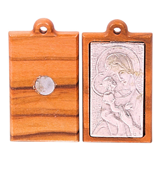 Olive wood magnet featuring a silver-toned metal relief of Mary holding baby Jesus on the front, set within a natural wood frame. The reverse side shows the plain wood with a central circular magnet embedded for attachment to metal surfaces.