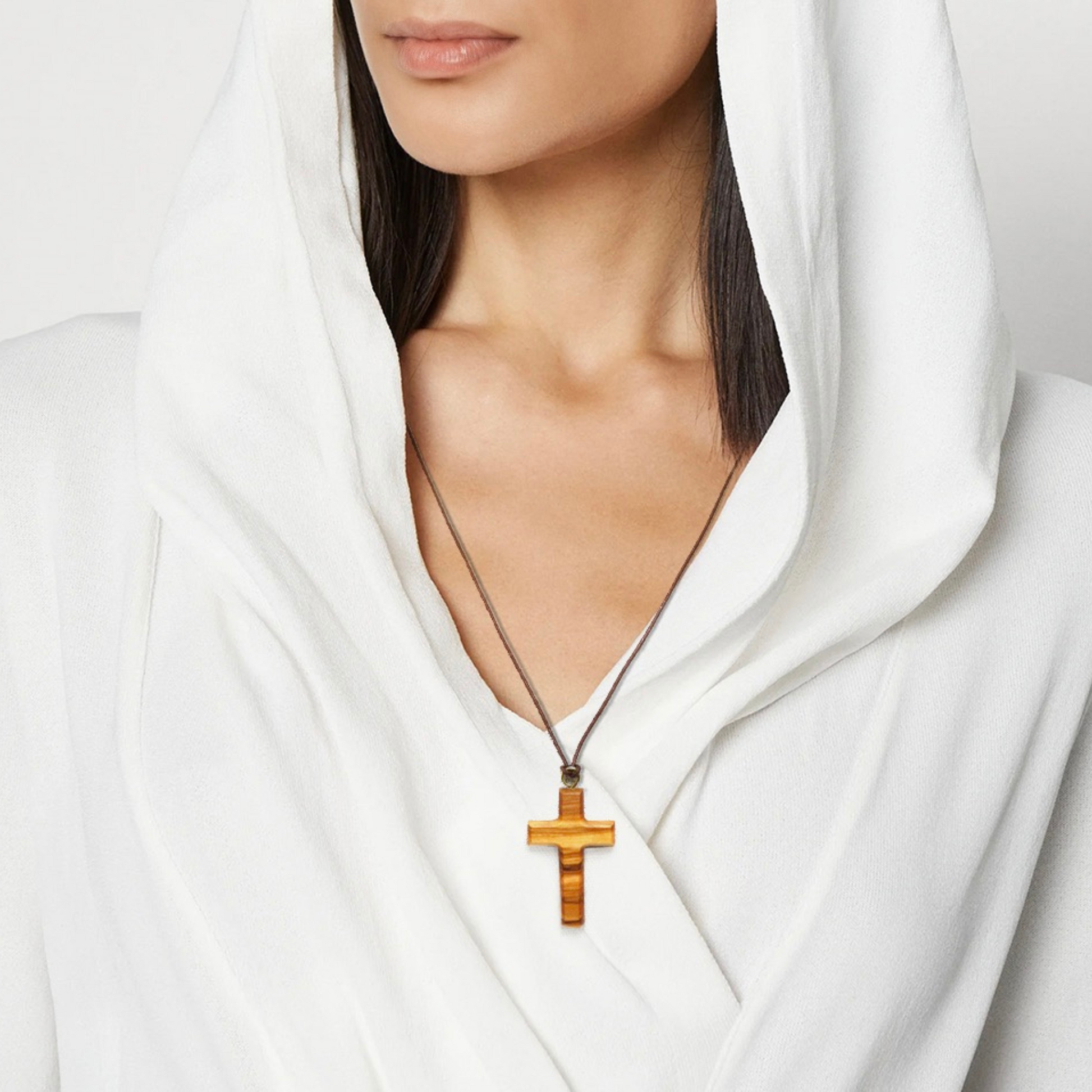Woman wearing a white garment with an olive wood cross necklace