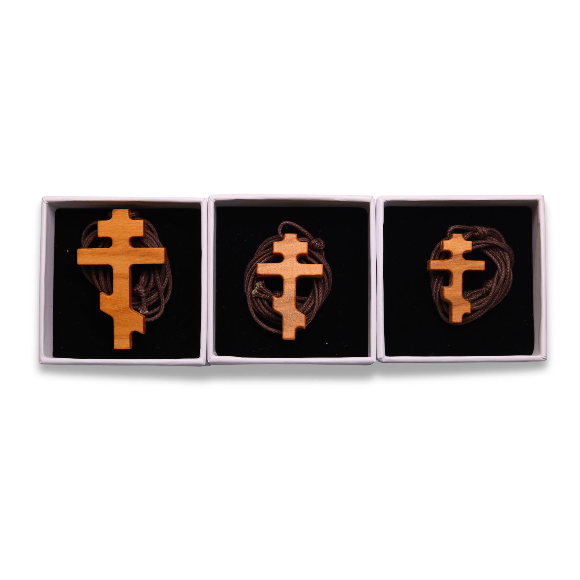 Russian orthodox olive wood cross pendant on a white background in three boxes