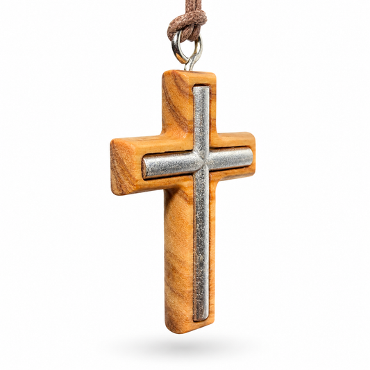 A wooden cross pendant necklace with a polished silver metal center and a brown cord, shown on a plain white background at an angle