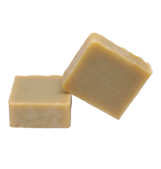  Two square soap bars with a soft beige color, positioned one leaning against the other. The soaps are made with natural ingredients including olive oil, babassu seed oil, and shea butter, crafted by Christian families in the Holy Land.