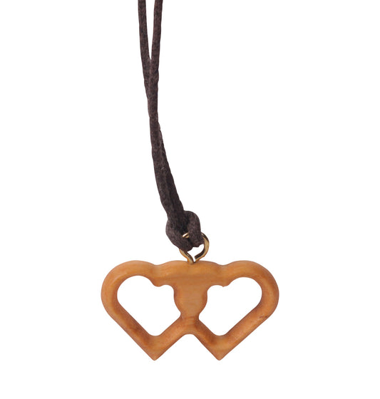 This pendant is an intricate carving made from olive wood that symbolizes two intertwined hearts. The two hearts share a common center, almost like they are holding onto each other, and their outlines merge fluidly. The wooden surface is smooth, and its natural grain patterns offer a gentle texture, evoking the earthy warmth and richness that olive wood typically possesses.