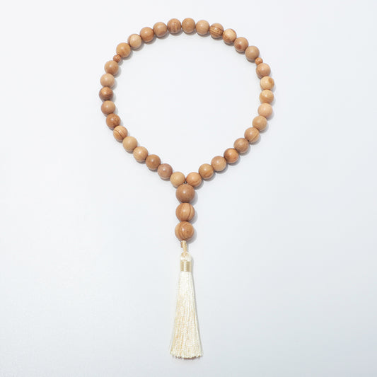 Full front view of olive wood prayer beads with two small dividers and three beads above a cream tassel