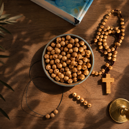Wooden beads in a bowl with a rosary and bible on a brown surface