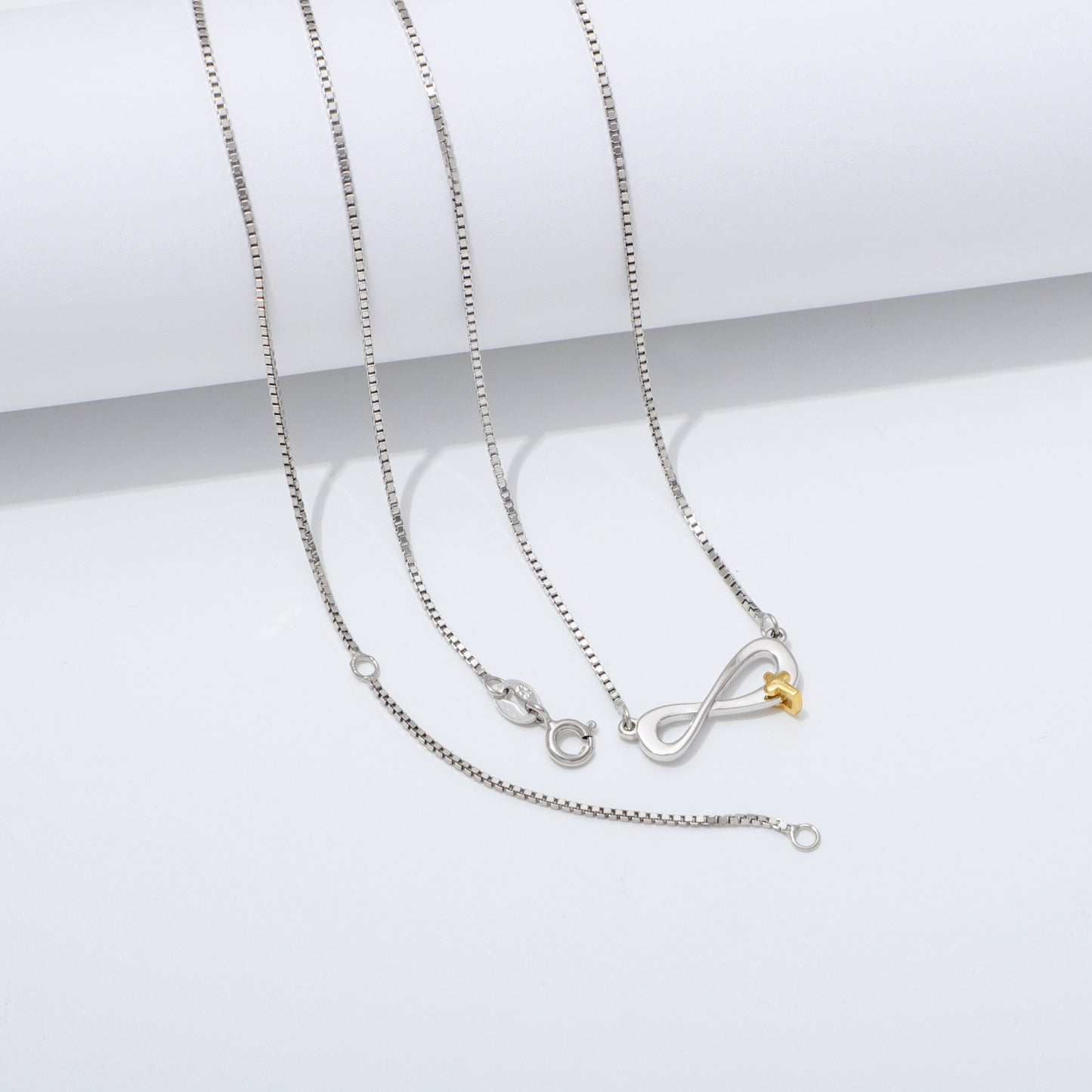 Silver 925 Sterling infinity necklace with a gold cross pendant on a white background