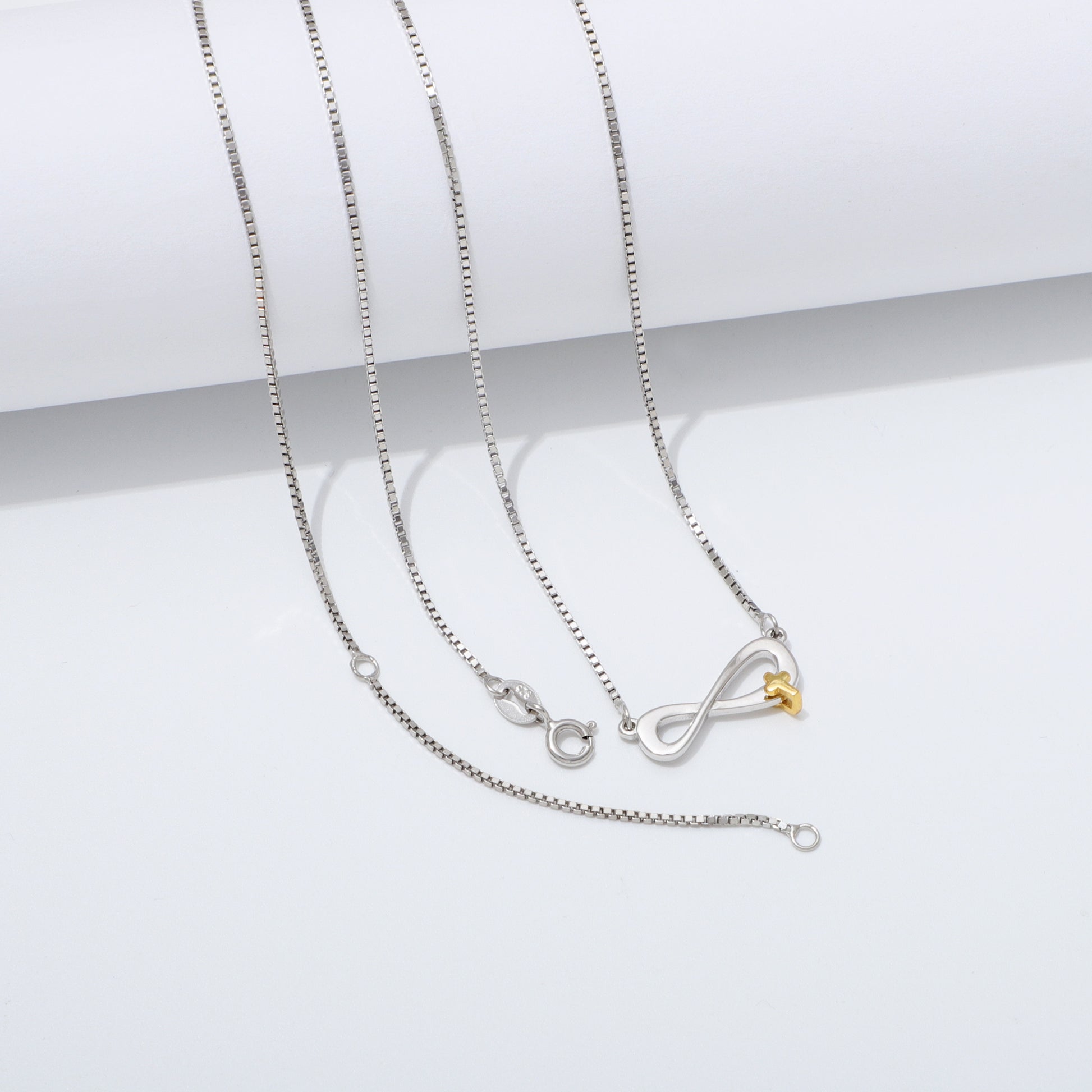 Silver 925 Sterling infinity necklace with a gold cross pendant on a white background