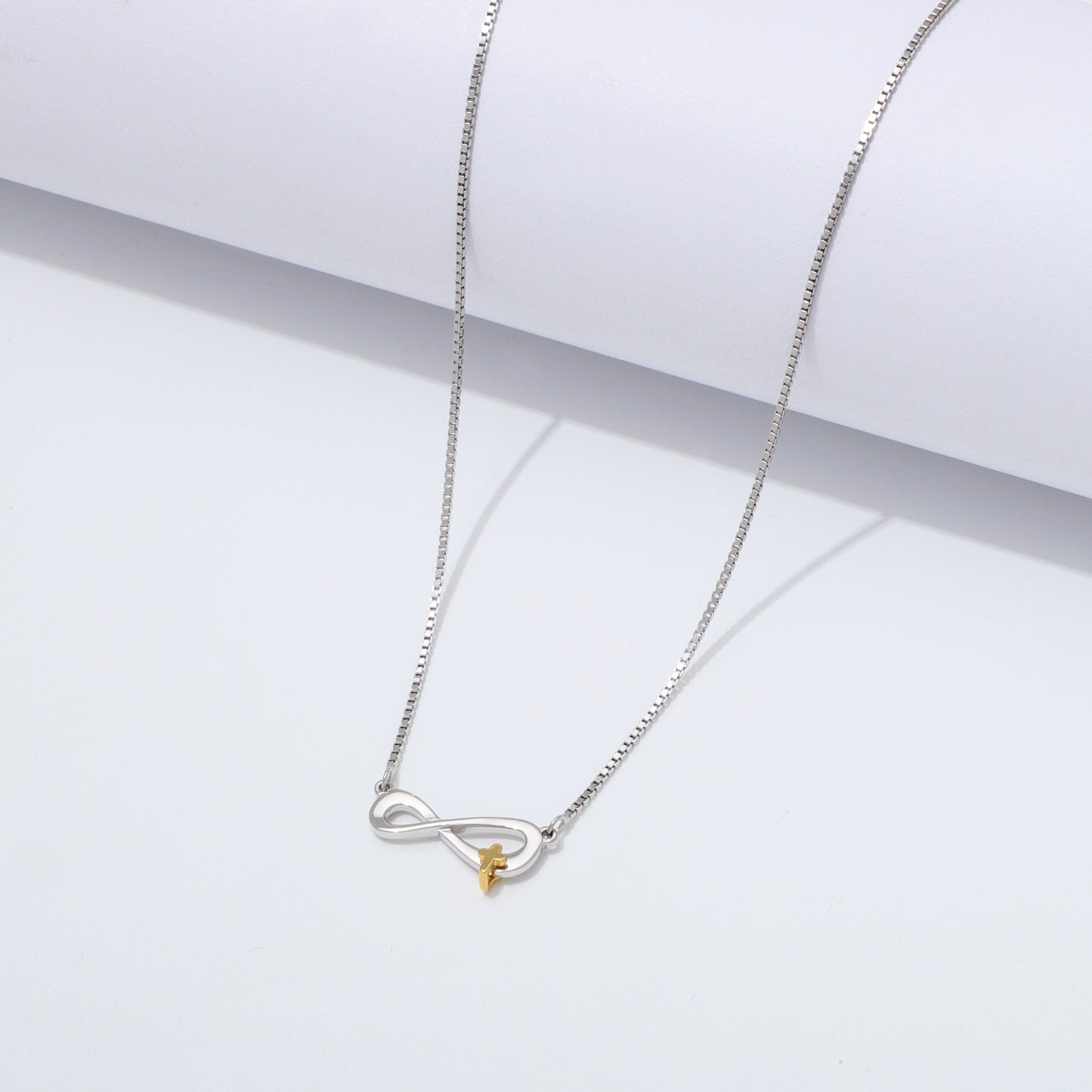 Silver 925 Sterling infinity necklace with a gold cross pendant on a white background