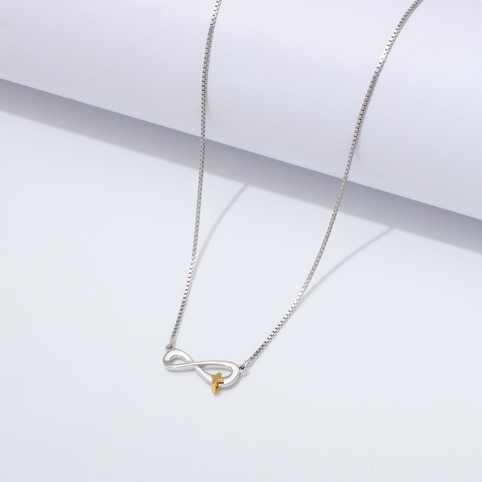 Silver 925 Sterling infinity necklace with a gold cross pendant on a white background