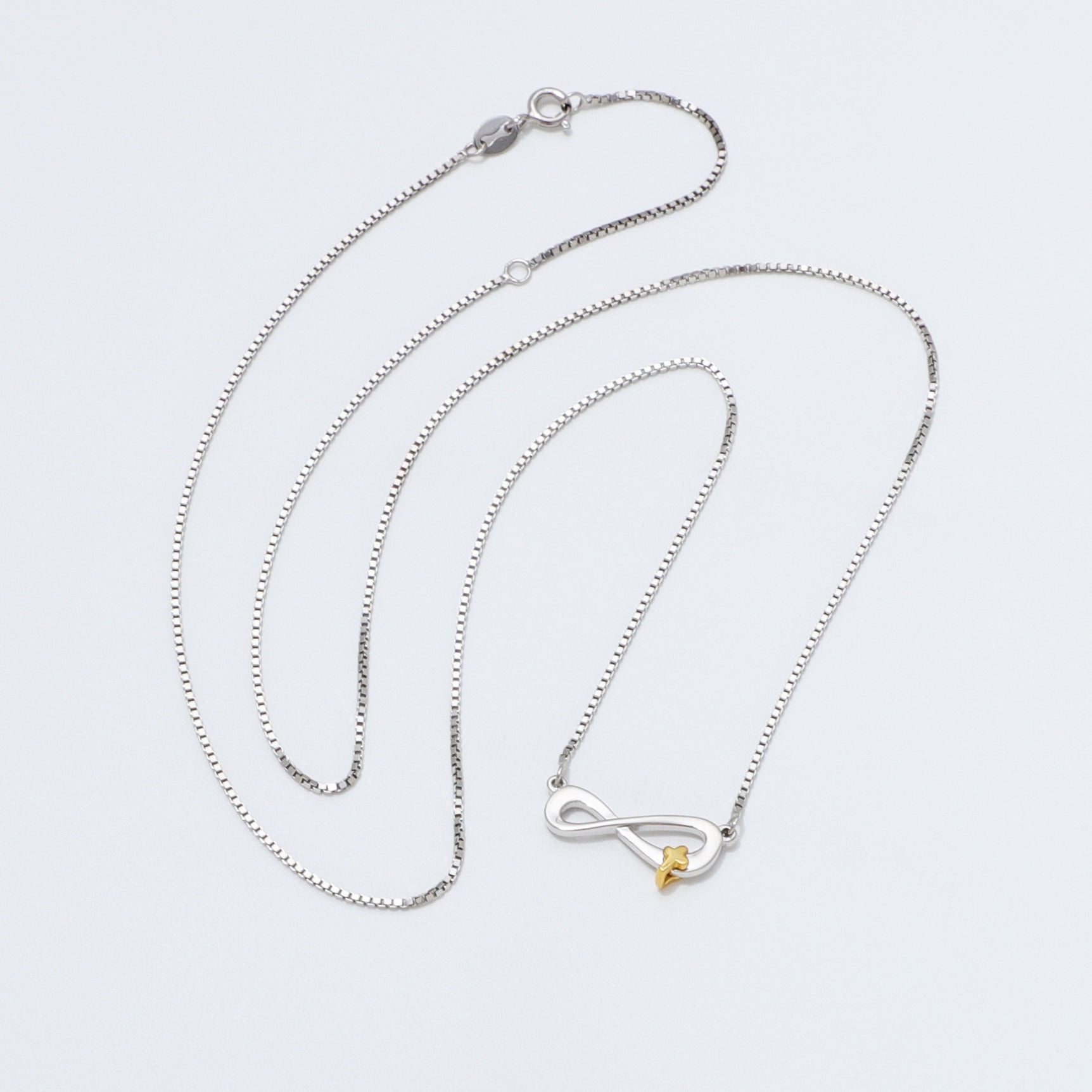 Silver 925 Sterling infinity necklace with a gold cross pendant on a white background
