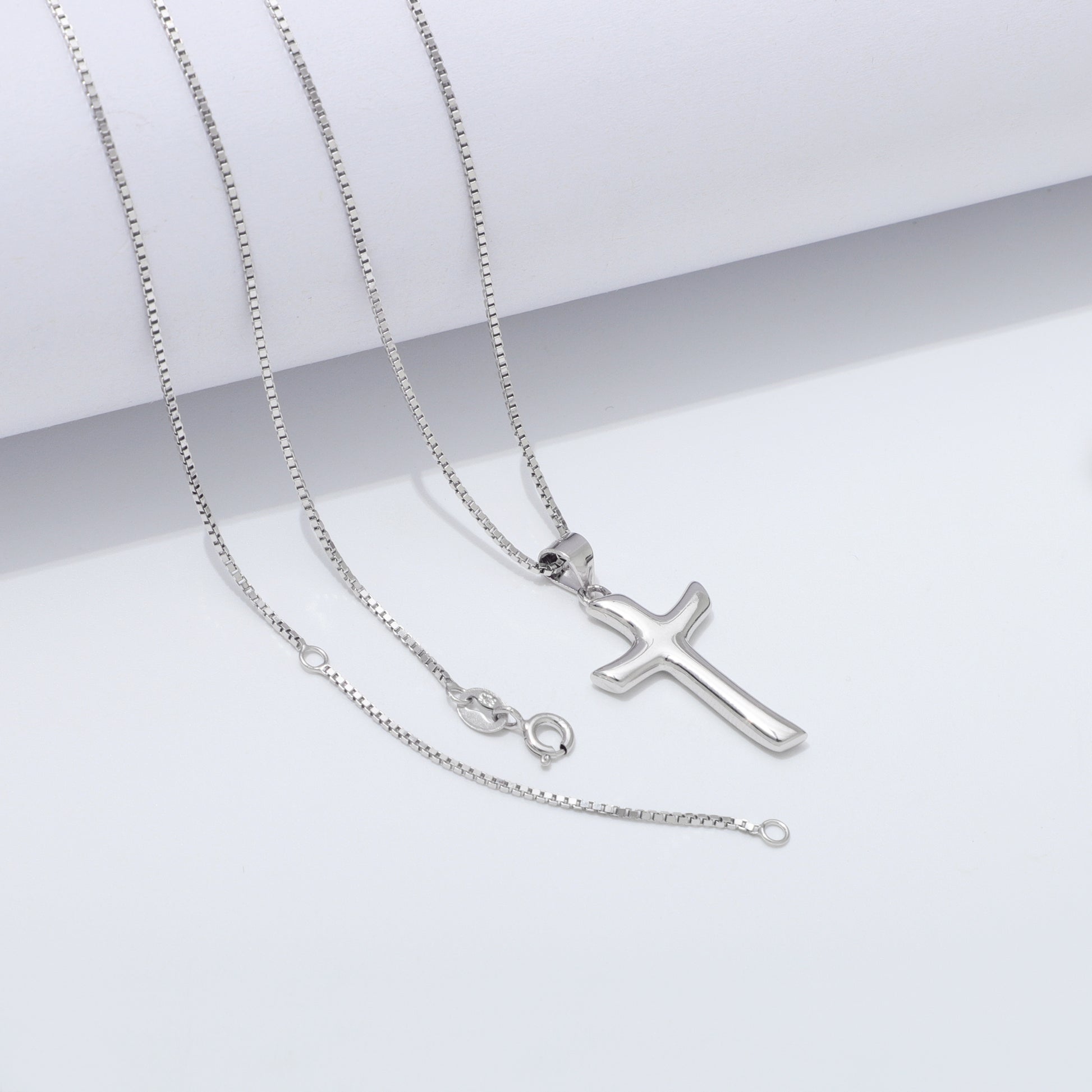 Silver cross necklace on a white background