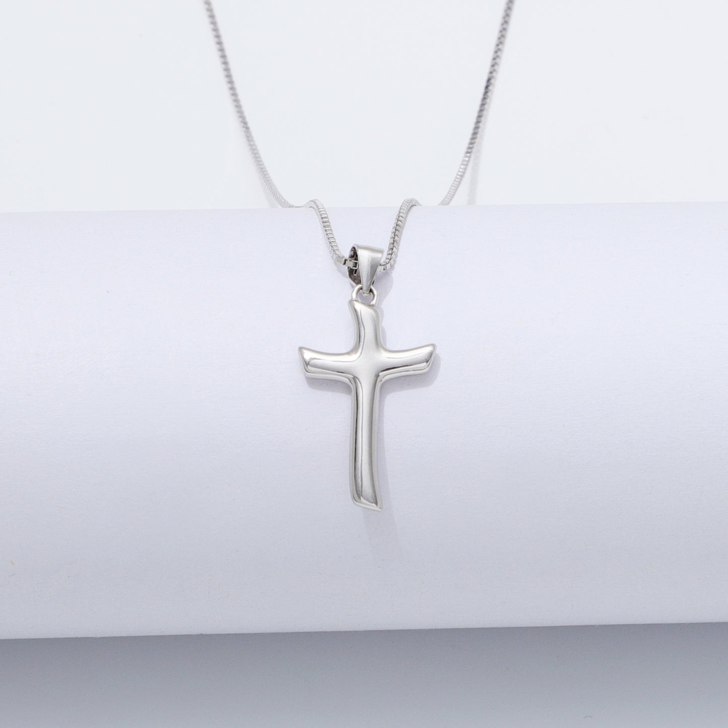 Silver cross pendant necklace on a white background