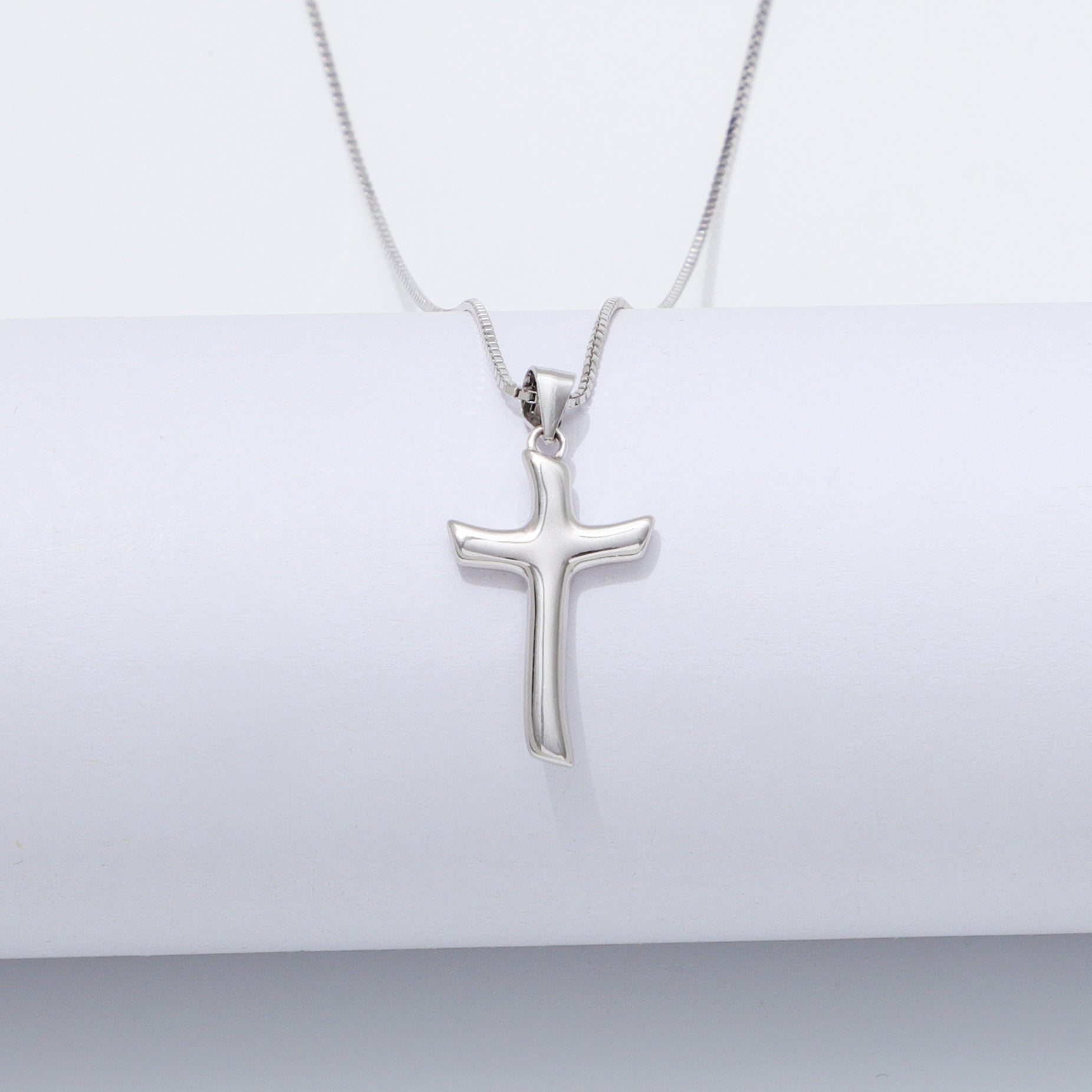 Silver cross pendant necklace on a white background