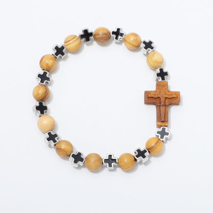 A beaded rosary-style bracelet featuring light brown wooden beads, black cross-shaped beads with silver borders, and a larger wooden cross pendant, displayed on a clean white background.
