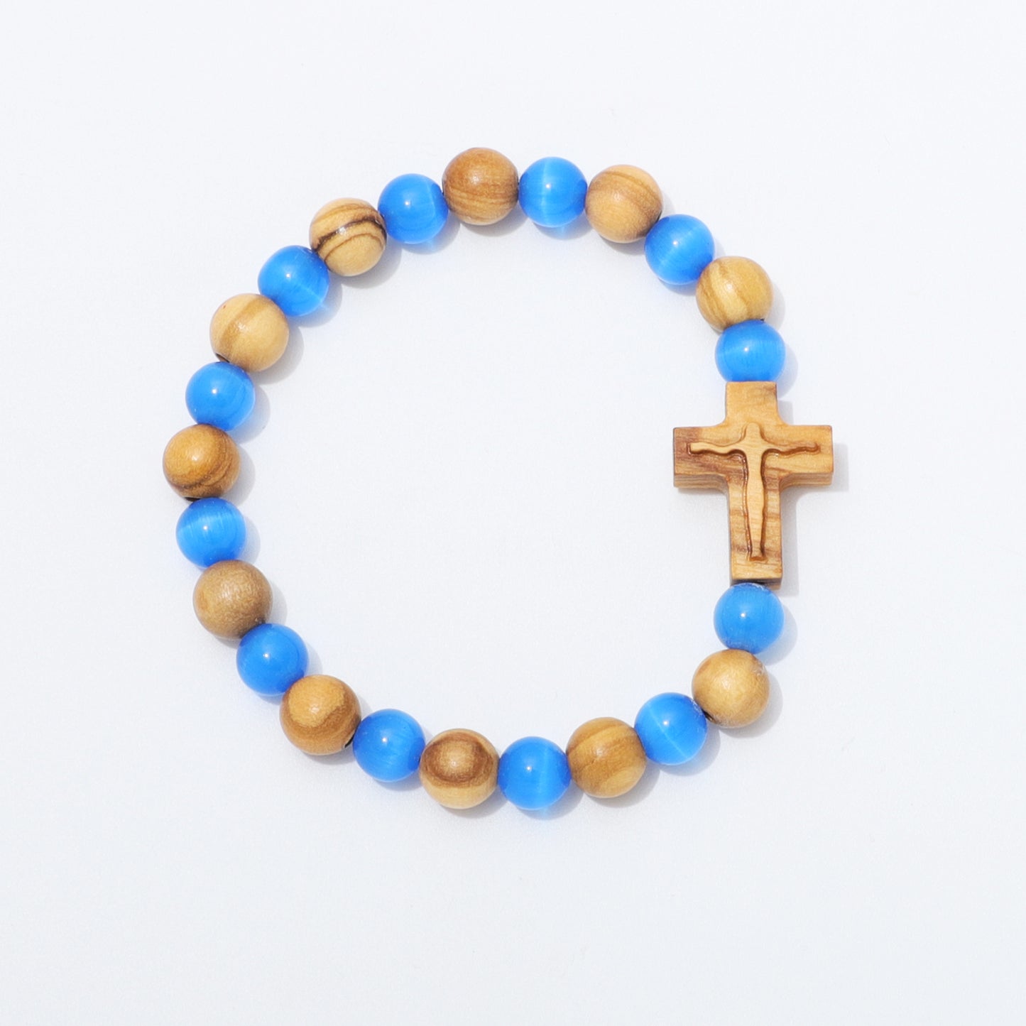 A beaded bracelet featuring alternating bright blue and natural light brown wooden beads, completed with a small carved wooden cross on a plain white background.