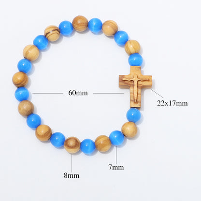 A beaded bracelet with alternating blue and natural wood beads, featuring a wooden crucifix pendant. Black measurement lines and text labels indicate dimensions: 60mm for the bracelet circumference, 22x17mm for the crucifix, 8mm for some beads, and 7mm for others, all on a plain white background.