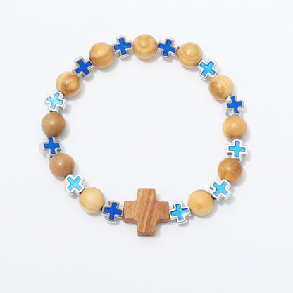 A beaded stretch bracelet featuring natural wood beads, a central wooden cross, and alternating blue and light blue enamel cross charms set in silver-tone metal, displayed on a clean white background.