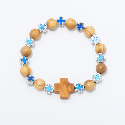 A beaded stretch bracelet featuring natural wood beads, light blue enamel cross charms, silver-plated cross charms, and a larger wooden cross at the bottom, displayed on a clean white background.
