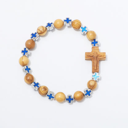 A beaded rosary-style bracelet with light brown wooden beads, small blue enamel crosses, and a larger wooden crucifix pendant, photographed on a clean white background.
