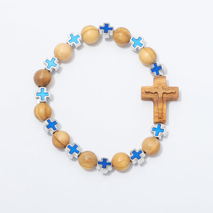 A beaded bracelet featuring natural wood beads, a wooden crucifix, and alternating blue and light blue enamel cross charms set in silver, displayed on a clean white background.