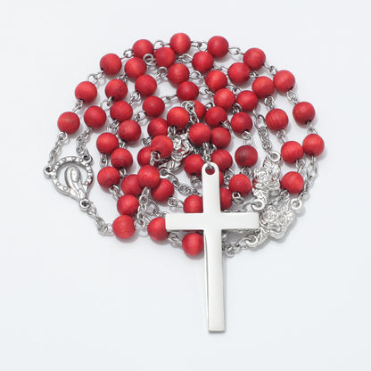 A rosary necklace featuring matte red wooden beads on a silver-tone metal chain, complete with a polished silver cross.