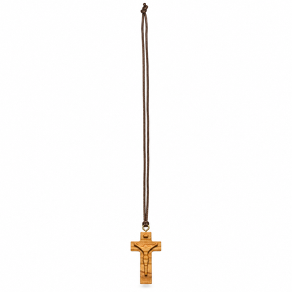A wooden crucifix pendant with an engraved figure of Jesus Christ, hanging from a dark brown cord on a plain white background.