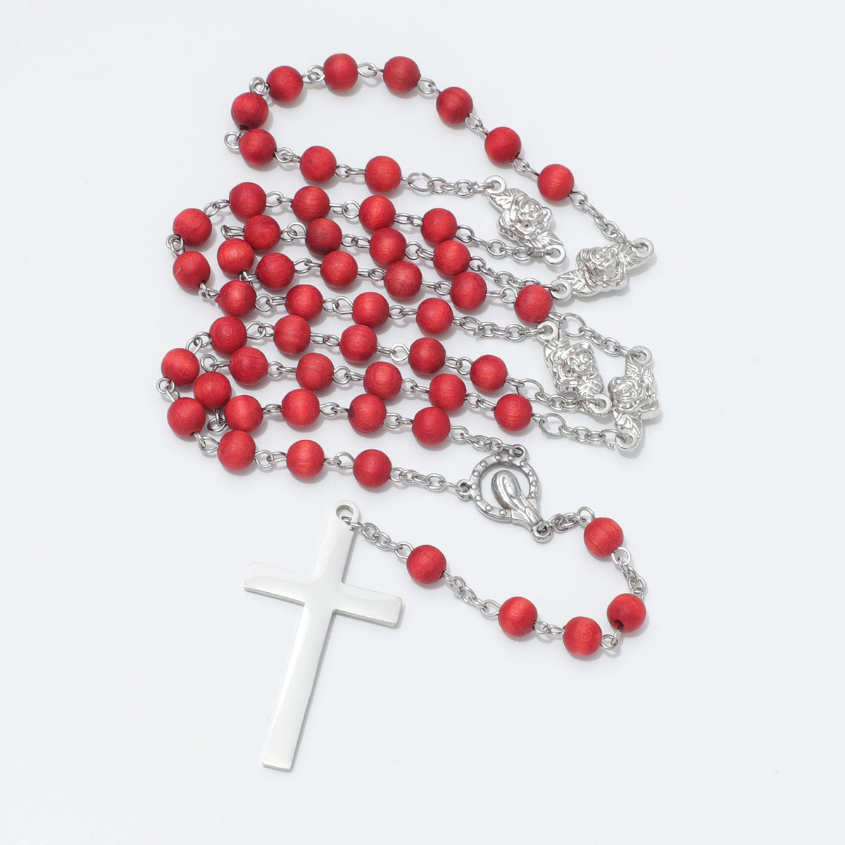 A rosary with matte red beads and silver-tone metal links, chain, centerpiece, and cross, arranged on a plain white background.