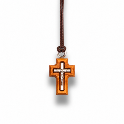 Wooden cross pendant with silver Jesus figure on a brown cord against a white background