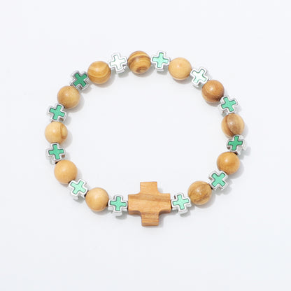 A beaded bracelet featuring natural wood beads, a central wooden cross, and alternating mint green and white enamel cross charms on a white background.
