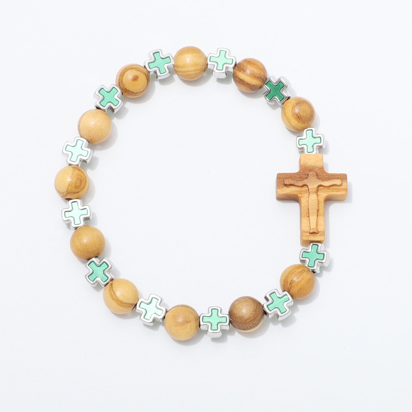 A wooden beaded bracelet featuring light brown olive wood beads, a carved wooden crucifix, and mint green enamel cross charms outlined in silver, displayed on a clean white background.