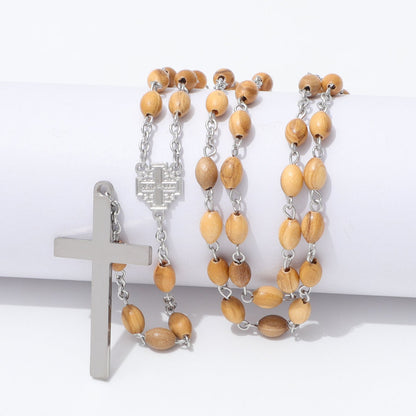 A rosary-style necklace with light tan wooden beads and silver-tone metal links, cross, and centerpiece, displayed on a white cylindrical prop against a white background.