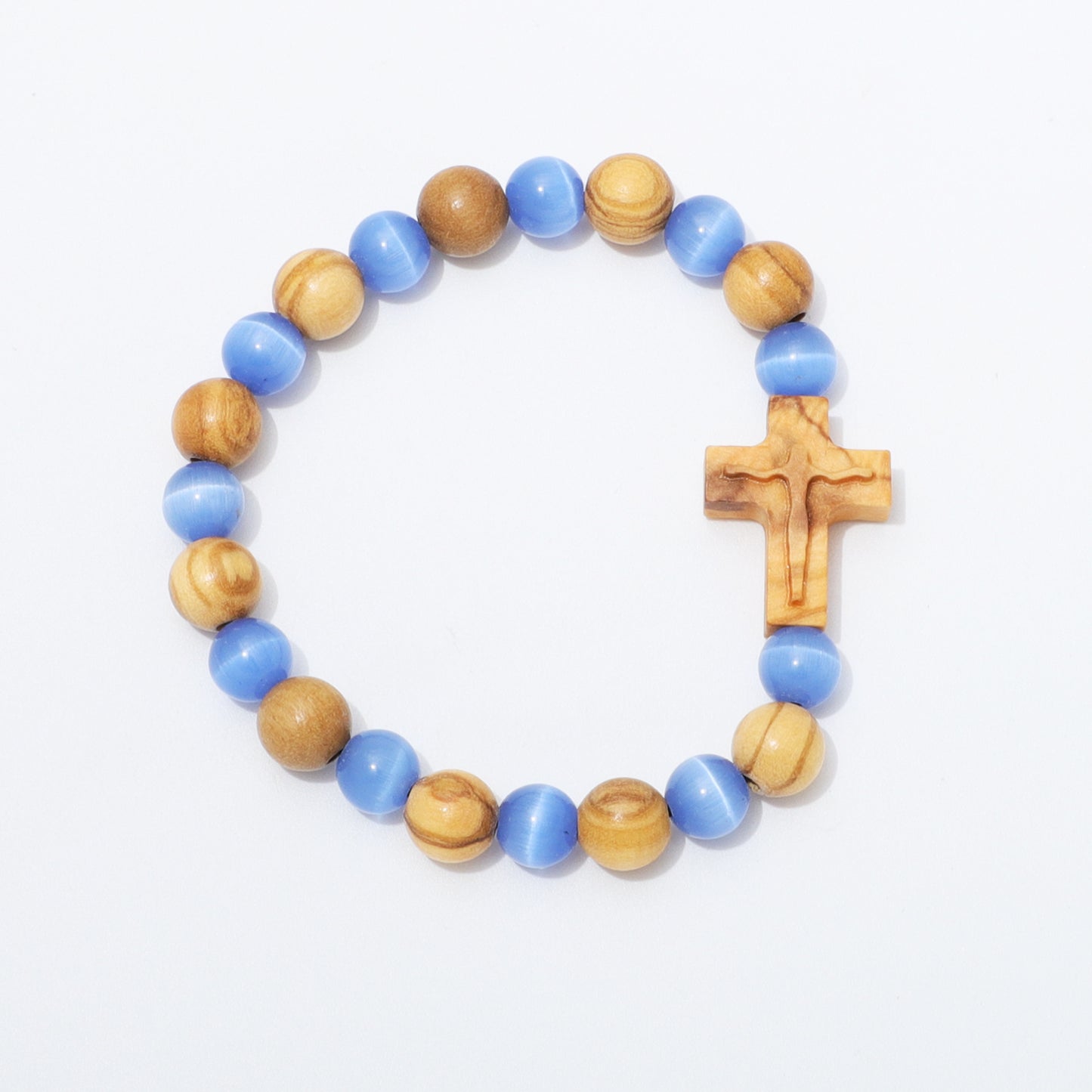 A beaded stretch bracelet featuring alternating light blue and natural wood beads, with a small carved wooden cross on the side, displayed on a clean white background.