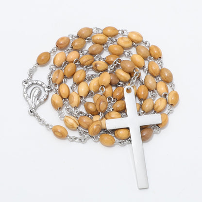 A rosary necklace featuring light brown wooden beads on a silver-tone chain, with a polished silver cross pendant and a decorative silver clasp, displayed on a clean white background.