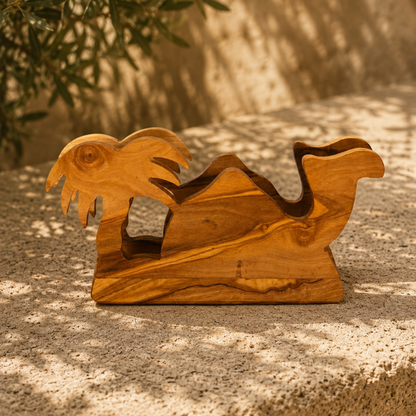 A hand-carved olive wood napkin holder, placed on a textured stone surface in warm natural light.