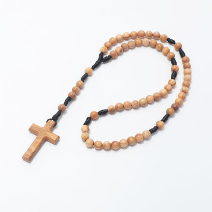 A wooden rosary with light brown beads, a matching wooden cross pendant, and black cord separators, displayed on a clean white background.