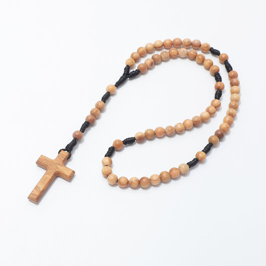 A wooden rosary with light brown beads, a matching wooden cross pendant, and black cord separators, displayed on a clean white background.