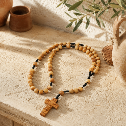 Wooden rosary with a cross on a textured surface with natural light