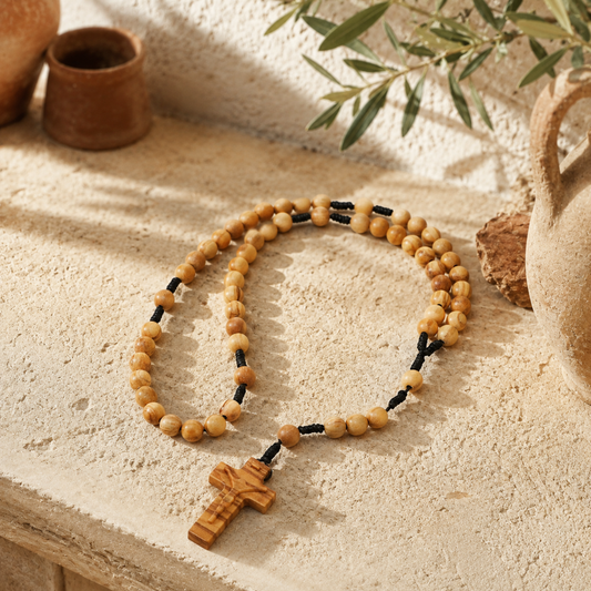 Wooden rosary with a cross on a textured surface with natural light