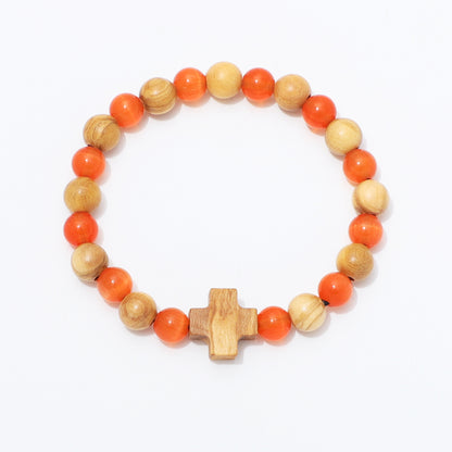 A beaded stretch bracelet featuring alternating orange and light natural wood beads, with a small wooden cross charm at the front, displayed on a clean white background.