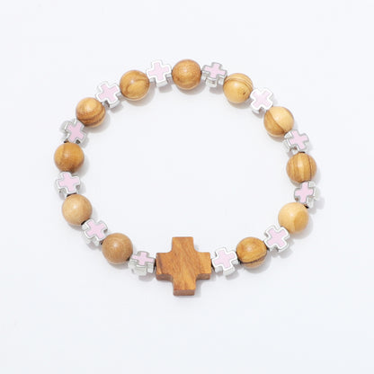 A wooden bead stretch bracelet featuring natural wood beads, silver-toned metal accents, light pink enamel crosses, and a larger central wooden cross, displayed on a clean white background.