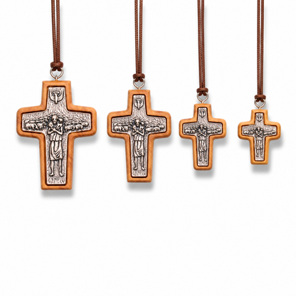 Four cross-shaped pendants on brown cords against a white background