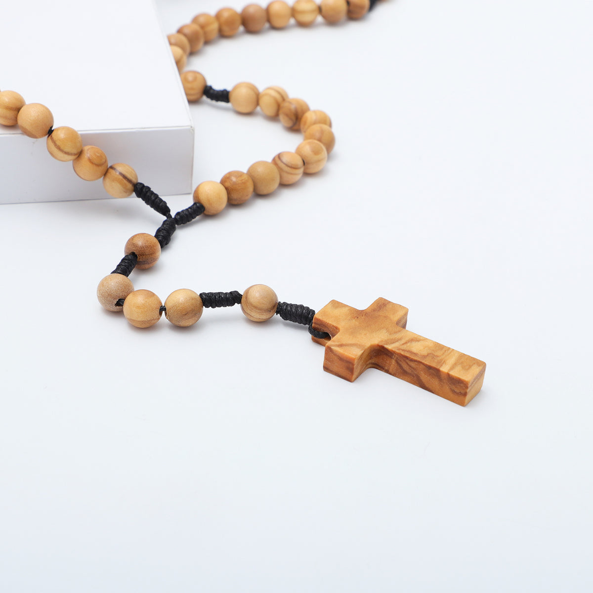 Close view of the olive wood cross and beads on knotted cord